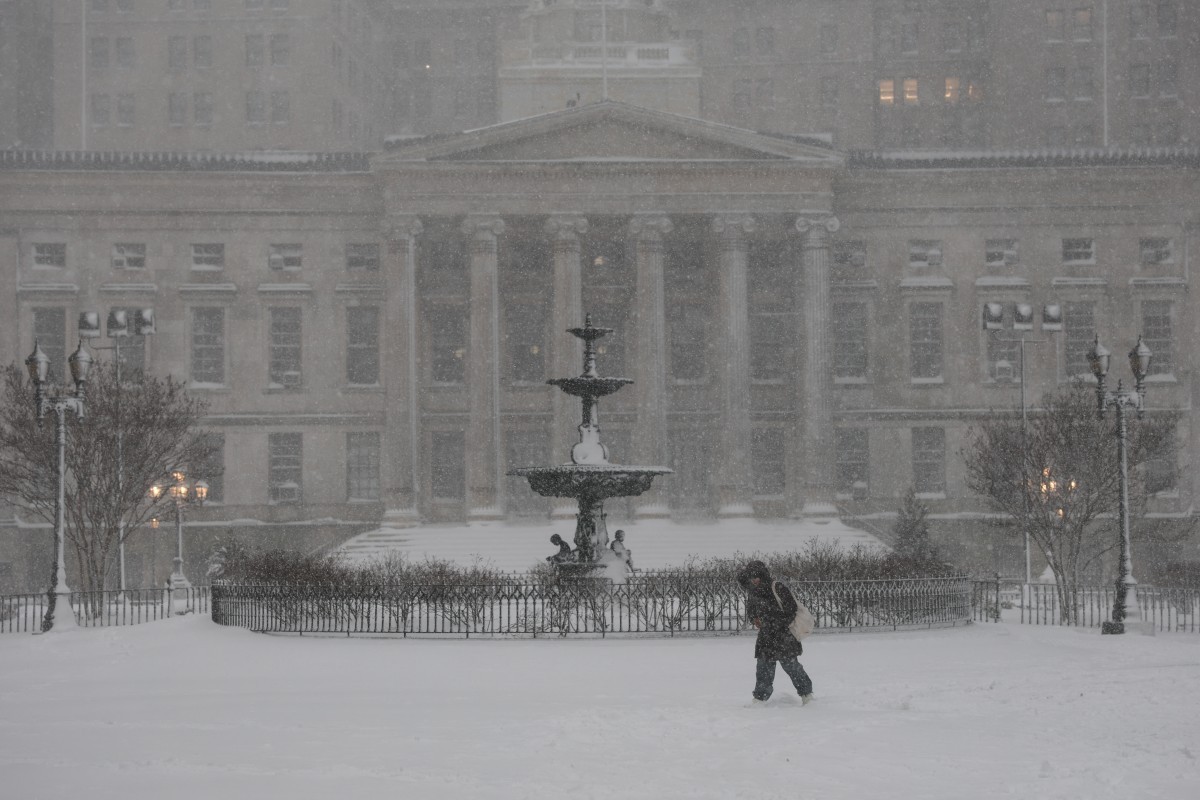 A person walks in the falling snow in the Brooklyn borough of New York City on February 23, 2026. New York ordered drivers off the road and shut down schools on Monday, while residents hunkered down f ...