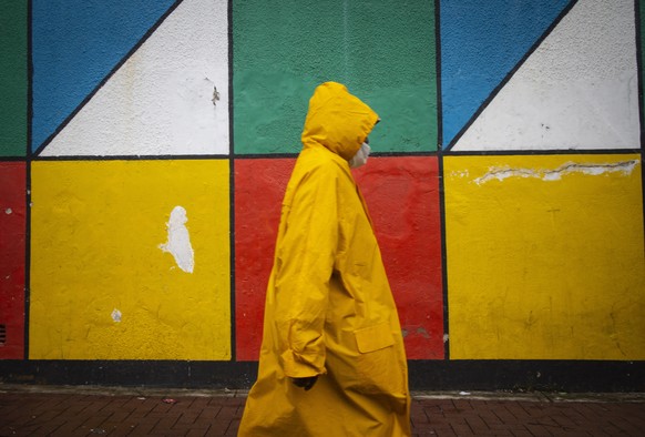 epa08981351 A man walks with his yellow rain coat as a rain shower crosses overhead during a second week of heavy rains in the interior of the country, Johannesburg, South Africa, 02 February 2021. Th ...