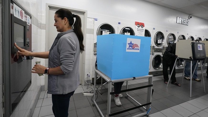 Stella Lopez puts cash on a laundry card at the Su Nueva Lavanderia near Chicago&#039;s Midway Airport, as residents vote Tuesday, Nov. 8, 2022, in Chicago. (AP Photo/Charles Rex Arbogast)