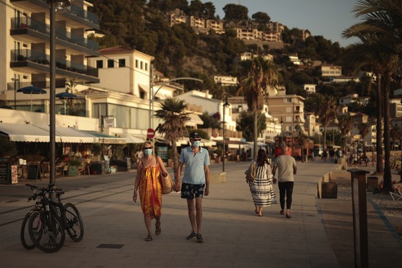 Tourists and locals walk in town of S�3ller in the Balearic Island of Mallorca, Spain, Wednesday, July 29, 2020. Concerns over a new wave of coronavirus infections brought on by returning vacationers  ...