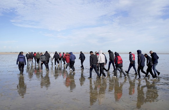 A group of people thought to be migrants walk up the beach after being brought in to Dungeness, Kent, onboard the RNLI Dungeness Lifeboat, following a small boat incident in the Channel, Tuesday May 1 ...