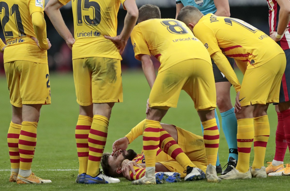 Barcelona's Gerard Pique, bottom, reacts after getting an injury during the Spanish La Liga soccer match between Atletico Madrid and FC Barcelona at the Wanda Metropolitano stadium in Madrid, Spa ...