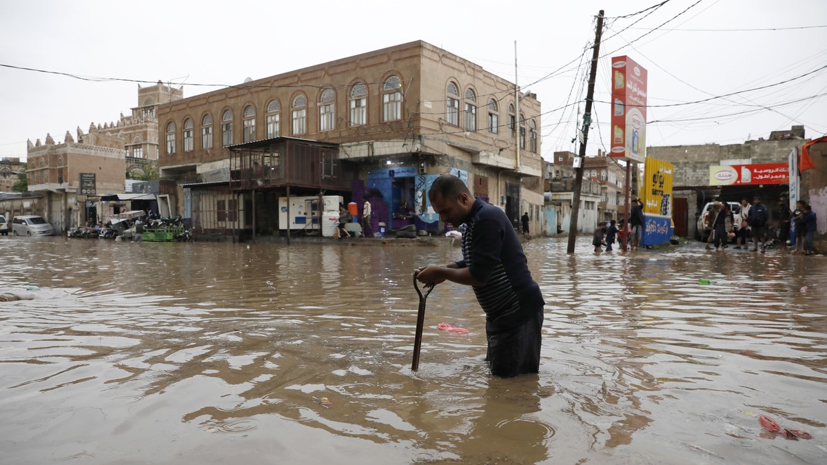 epa10101770 A Yemeni tries to open a sewer drain as rainwater flood a street following a heavy rainfall in Sana'a, Yemen, 01 August 2022. Torrential rains and associated floods have hit several a ...