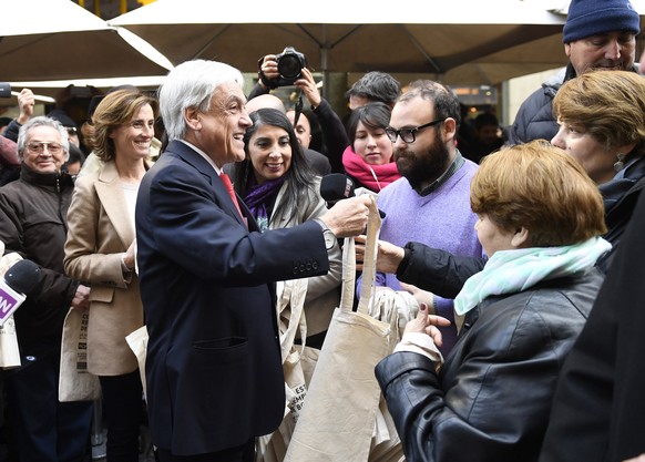 epa06925713 A handout picture provided by the Chilean Presidency, shows the Chilean President Sebastian Pinera (L) who delivers cloth reusable bags to citizens in the center of Santiago, Chile, 03 Aug ...