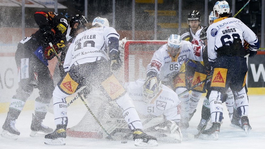 Zugs Torhueter Luca Hollenstein, umringt von Zugern und Bernern, haelt einen Puck fest, im Eishockey Meisterschaftsspiel der National League zwischen dem SC Bern und dem EV Zug, am Freitag, 4. Dezembe ...