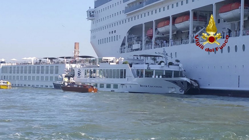 In this photo released by the Italian Firefighters, the MSC Opera cruise liner, a towering cruise ship, strikes a tourist river boat, left, Sunday, June 2, 2019, in Venice, Italy, injuring at least fi ...