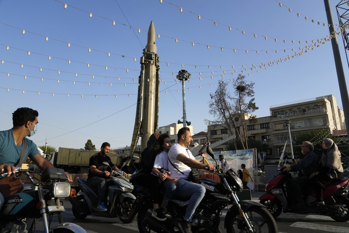 People ride their motorcycles in front of a Qiam missile displayed in an exhibition by Iran's army and paramilitary Revolutionary Guard celebrating "Sacred Defense Week" commemorating t ...