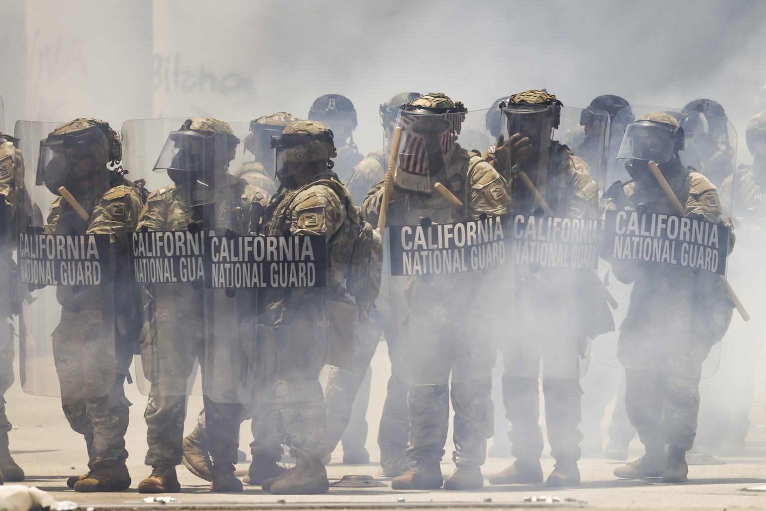 epa12164940 Members of the California National Guard seen through clouds of tear gas in front of the Edward R. Roybal Federal Building in Los Angeles, California, USA, 08 June 2025. US President Donal ...