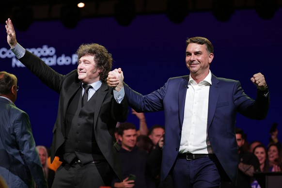 Brazilian Sen. Flavio Bolsonaro, right, and Argentina's President Javier Milei greet supporters during the Liberal Party convention where Bolsonaro was confirmed as the party's presidential  ...