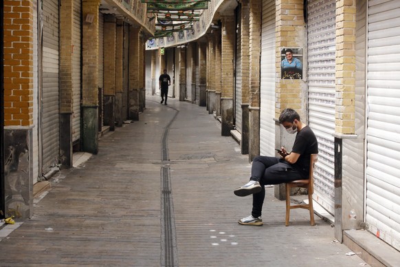 epa09416227 An Iranian man wearing a face mask sits next to his closed shop in Tajrish old bazaar in Tehran, Iran, 16 August 2021. Iranian authorities began a one-week lockdown, from 16 August until 2 ...