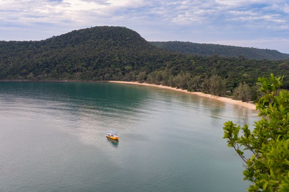 A drone view of the sea surrounded by greenery in Koh Rong Samloem, Cambodia xkwx aerial beach blue boat cambodia drone horizon koh rong samloem landscape mountain nature ocean peaks sand scenic shore ...