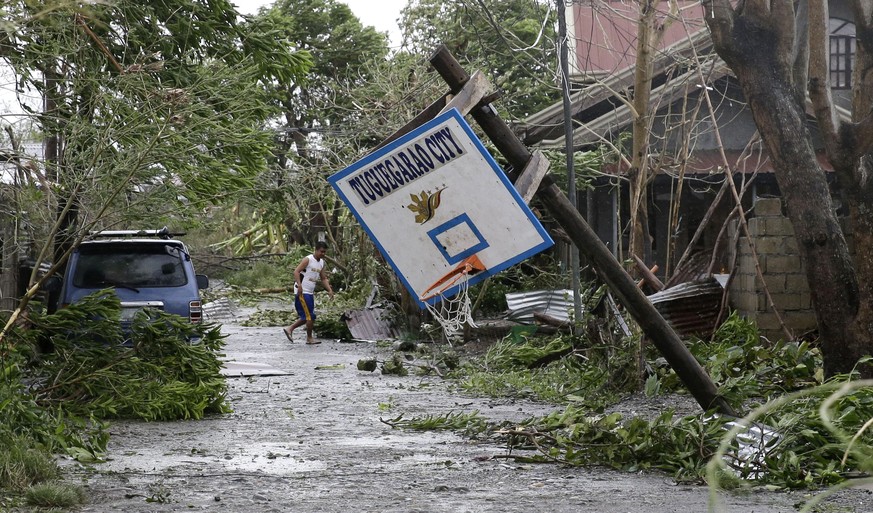 FILE - In this Saturday, Sept. 15, 2018, file photo, a resident walks beside a toppled basketball court after Typhoon Mangkhut barreled across Tuguegarao city, Cagayan province, northeastern Philippin ...