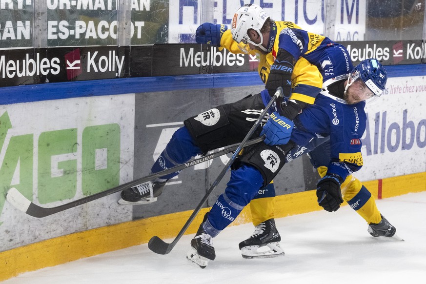 Nathan Marchon (HCFG) en bleu, lutte pour le puck Calle Andersson (HCD) lors du sixieme match de la finale des play-off du championnat suisse de hockey sur glace de National League entre le HC Fribour ...