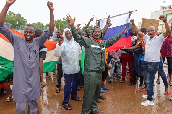 epa10771228 Supporters of putschist soldiers hold Niger&#039;s flags as they celebrate outside the National Assembly building in Niamey, Niger, 27 July 2023. Mutinous soldiers calling themselves the N ...