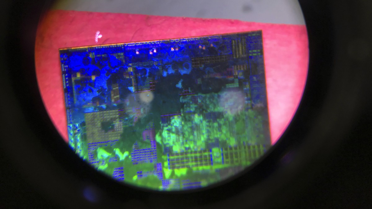 FILE - A Chinese microchip is seen through a microscope set up at the booth for the state-controlled Tsinghua Unigroup project which is driving China's semiconductor ambitions during the 21st Chi ...