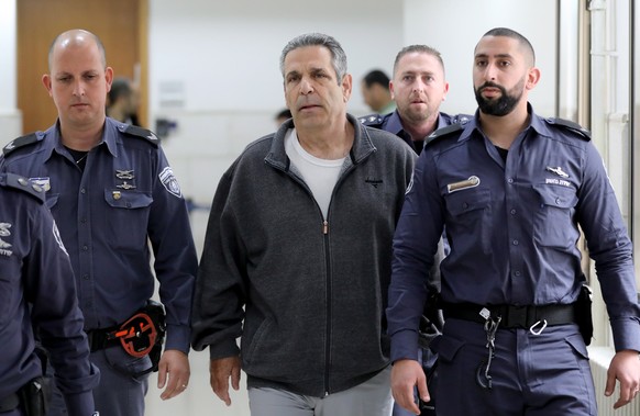 epa07398202 Gonen Segev (C), a former Israeli cabinet minister indicted on suspicion of spying for Iran, is escorted by prison guards as he arrives at court in Jerusalem, 26 February 2019. Media repor ...