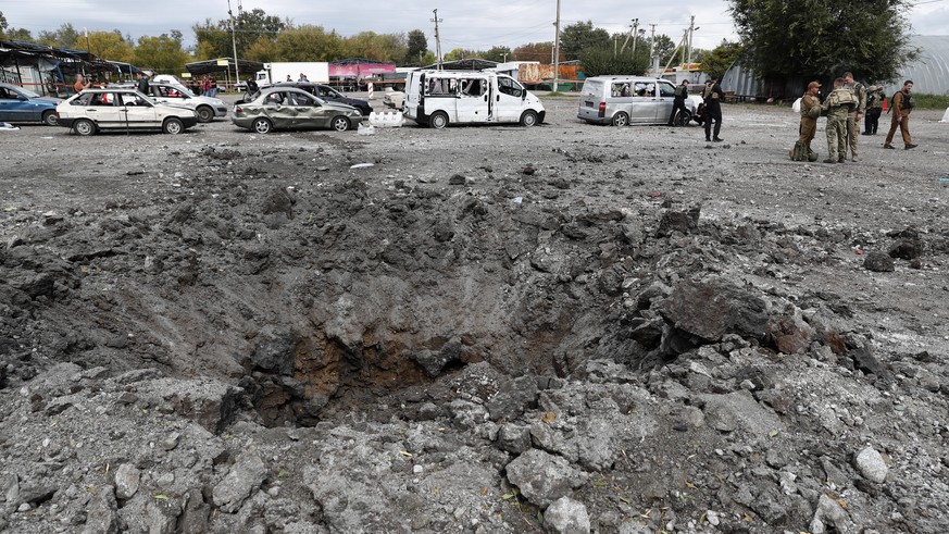epa10215323 A crater at the scene in Zaporizhzhia, Ukraine, 30 September 2022, where a convoy of civilians was struck by a Russian missile. At least 23 people have been killed and dozens more injured  ...