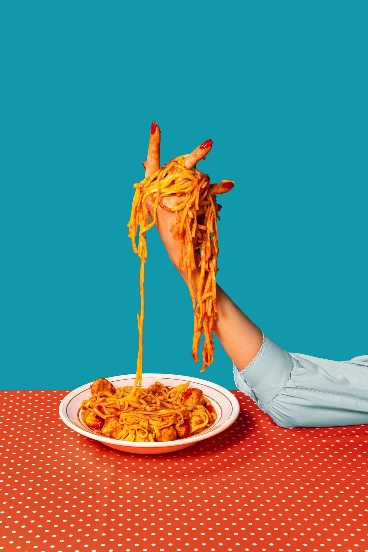 Surrealism. Food pop art photography. Female hands tasting spaghetti with meatballs on plaid tablecloth isolated on bright blue background. Vintage, retro style interior. Complementary colors