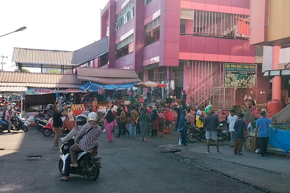 People wait outside after evacuating a market following an earthquake in Pekanbaru, Indonesia, Friday, Feb. 25, 2022. A strong and shallow earthquake hit off the coast of Indonesia&#039;s Sumatra isla ...