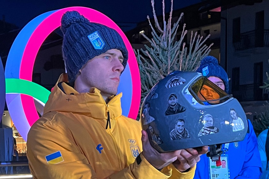 Ukraine's Vladyslav Heraskevych holds up his crash helmet during a press conference following a skeleton training session at the 2026 Winter Olympics, in Cortina d'Ampezzo, Italy, Tuesday, F ...