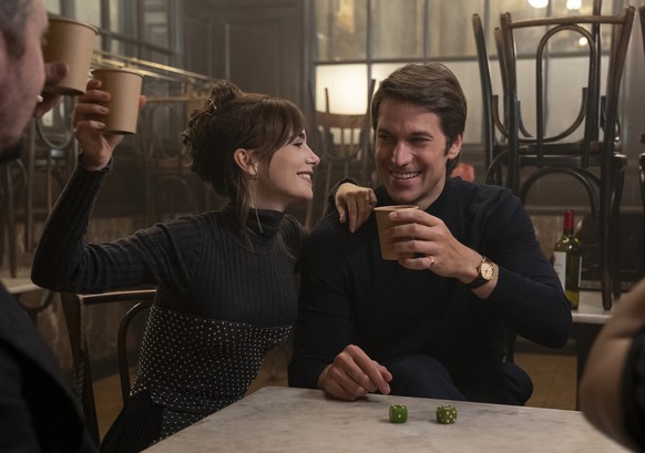 This image released by Netflix shows Lily Collins, left, and Lucas Bravo in a scene from &quot;Emily in Paris.&quot; (Stephanie Branchu/Netflix via AP)