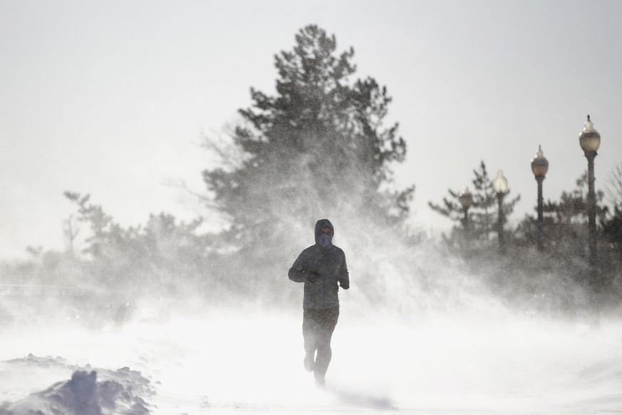 Gusty wind picks up snow accumulated on the ground as Jesse Sherwood, of Jersey City, N.J., jogs at Liberty State Park, Saturday, Jan. 6, 2018, in Jersey City. About 100 million people faced a new cha ...