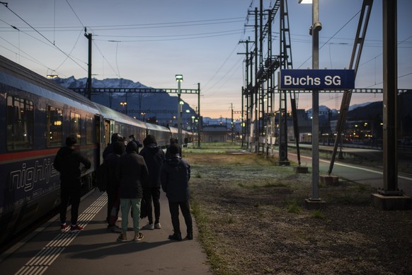 Grenzwaechter bringen Fluechtlinge aus einem Zug aus Wien zur Kontrolle, am Freitag, 19. November 2021, am Bahnhof in Buchs. Seit dem Sommer gelangen vermehrt afghanische Fluechtlinge an den Grenzbahn ...