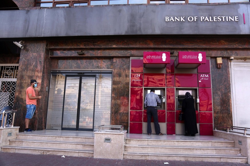 August 31, 2020: Gaza City, Palestine. 4 September 2020. Palestinian employees wear protective face masks and keep a distance as they queue near a cash machine outside the Bank of Palestine in Gaza Ci ...