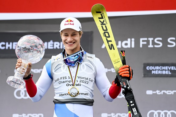 epa09838191 Marco Odermatt of Switzerland celebrates with the men&#039;s overall crystal globe trophy on the podium at the FIS Alpine Skiing World Cup finals in Meribel, France, 20 March 2022. EPA/URS ...