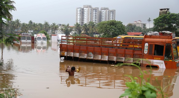 epa06952636 Indian man wade through flooded water in Kochi, Kerala state, India, 16 August 2018. According to reports, the region is on a high alert with schools and offices been closed due to the ris ...