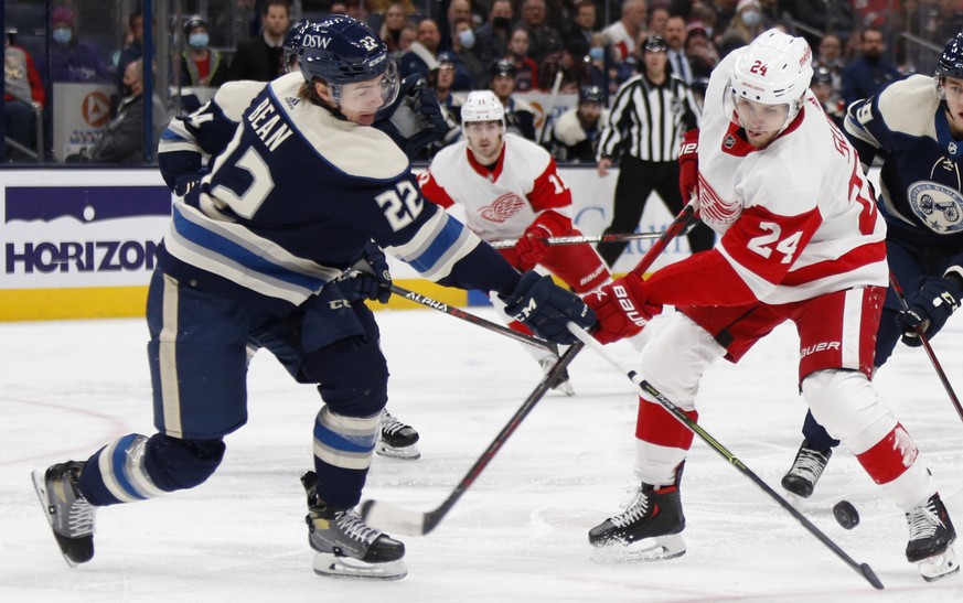Columbus Blue Jackets defenseman Jake Bean, left, tries to pass the puck past Detroit Red Wings forward Pius Suter during the first period of an NHL hockey game in Columbus, Ohio, Monday, Nov. 15, 202 ...