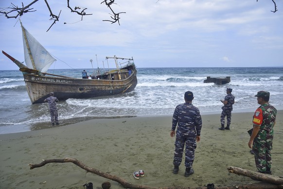 Indonesian military personnel inspect a wooden boat used to carry Rohingya refugees after it landed on Indra Patra beach in Ladong village, Aceh province, Indonesia, Sunday, Dec. 25, 2022. Dozens of h ...