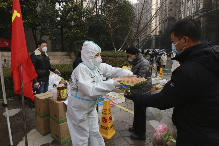 A community volunteer hands over eggs to a buyer at a temporary food store to provide supplies to residents outside a residential block in Xi&#039;an city in northwest China&#039;s Shaanxi province Mo ...