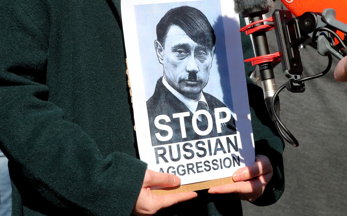 epa09784222 A protester in Sarajevo holds a photograph depicting Russian President Vladimir Putin as Adolf Hitler, during a protest against Russia's attack on Ukraine, in Sarajevo, Bosnia and Her ...