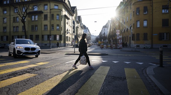 Eine Frau laeuft mit ihren Einkaeufen ueber einen Fussgaengerstreifen an der Limmatstrasse, aufgenommen am Mittwoch, 31. Januar 2024 in Zuerich.(KEYSTONE/Ennio Leanza)