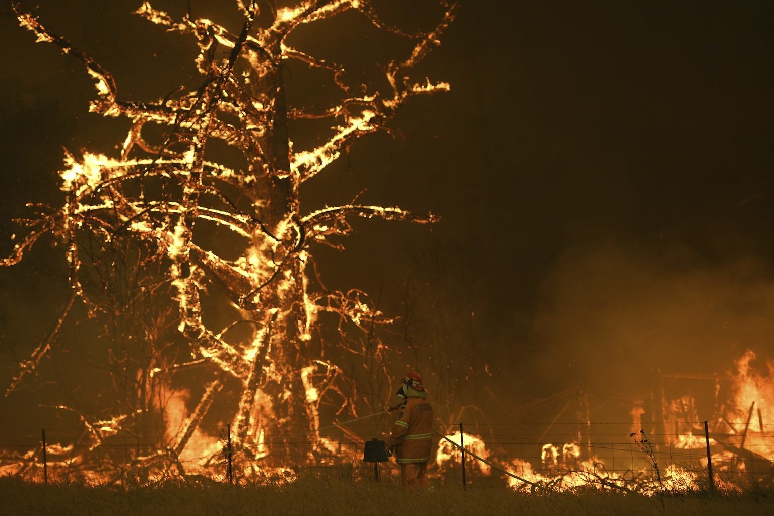 In this Saturday, Dec. 21, 2019, photo, NSW Rural Fire Service crew fight the Gospers Mountain Fire as it impacts a property at Bilpin, New South Wales state, Australia. Prime Minister Scott Morrison  ...