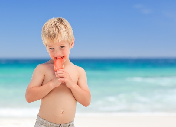 Little boy eats ice cream on the beach.