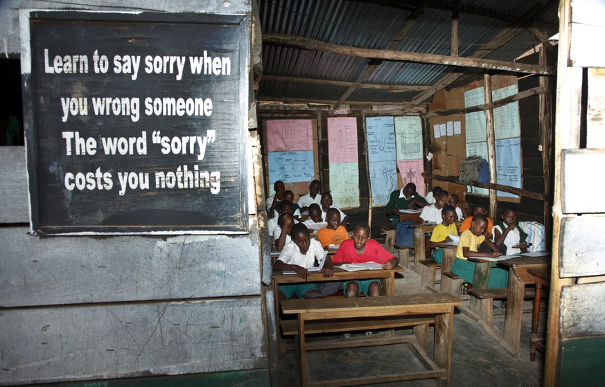 In this photo taken Friday, Oct. 14, 2016, pupils sit in a wood classroom at the Kibuye Junior Primary School where some scenes of a Disney film were filmed, in the Katwe slum of Kampala, Uganda. In a ...