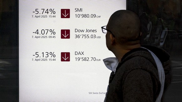 A man walks past a market board at the headquarters of the Swiss bank UBS in Zurich, Switzerland, on Monday, April 7, 2025 in Zurich, Switzerland. (KEYSTONE/Michael Buholzer)..