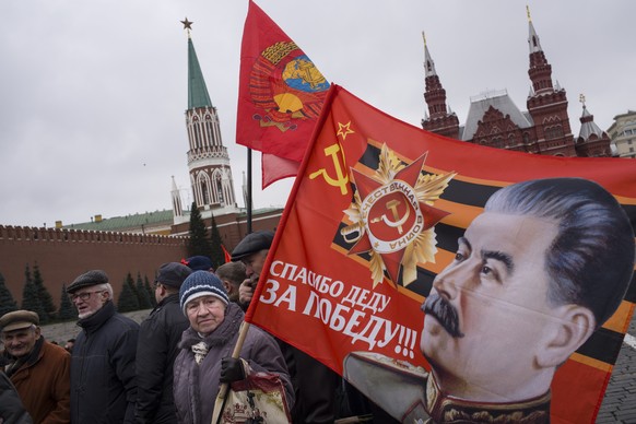 Communist party supporters carry flags with portraits of Soviet dictator Josef Stalin during a demonstration marking the 100th anniversary of the 1917 Bolshevik revolution in Red Square, in Moscow, Ru ...