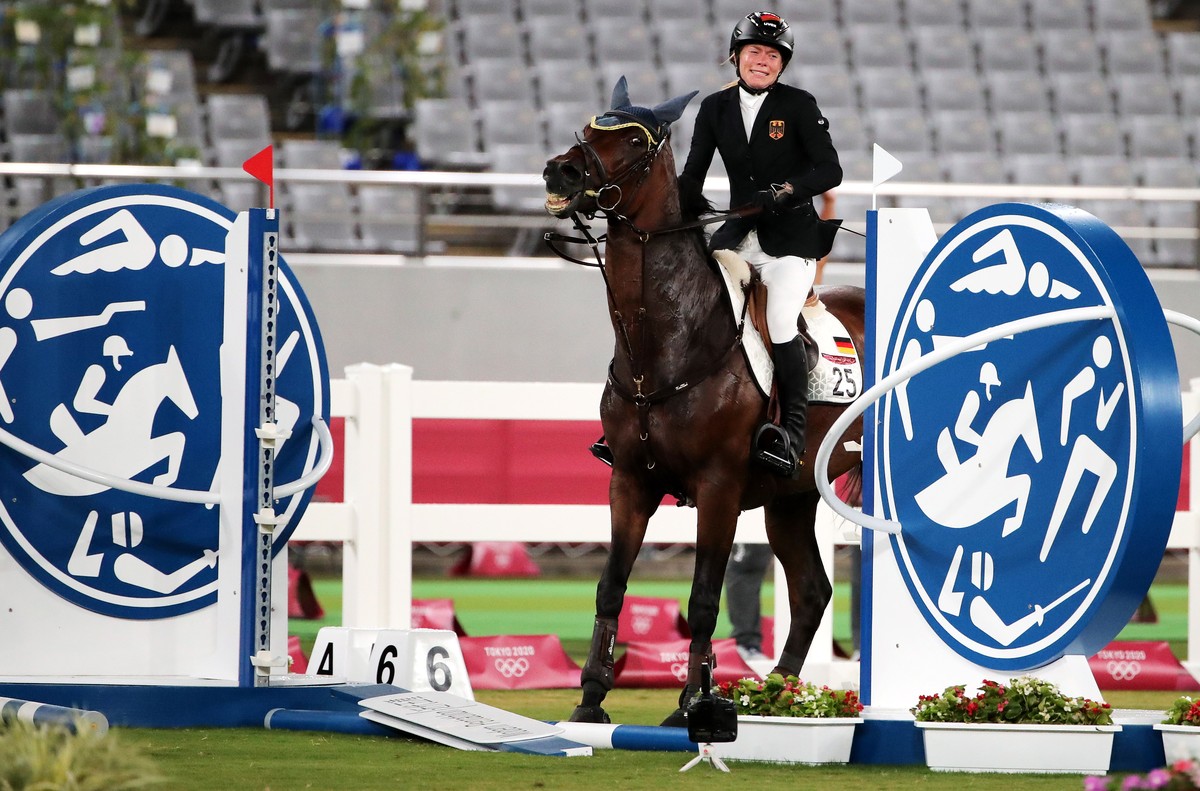 epa09400054 Annika Schleu of Germany on Saint Boy after hitting an obstacle as they compete in the Show Jumping portion of the Modern Pentathlon event at the Tokyo 2020 Olympic Games at the Tokyo Stad ...