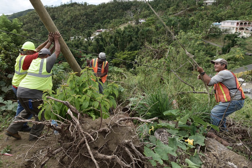 In this Jan. 31, 2018 file photo, Public Works Sub-Director Ramon Mendez, wearing a hard hat at left, works with locals who are municipal workers, from right, Eliezer Nazario, Tomas Martinez and Angel ...