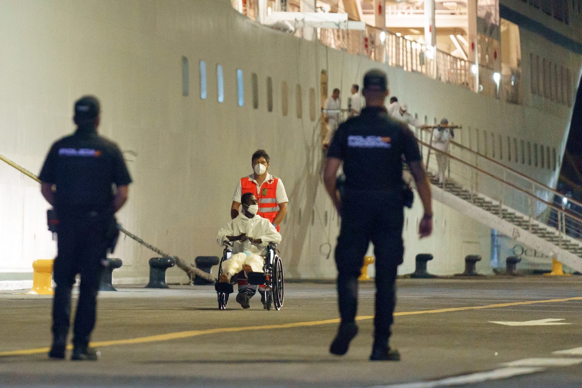 epa11427286 A migrant is helped by a Red Cross member after disembarking from the Insignia cruise ship at the port of Santa Cruz de Tenerife, Tenerife Island, Canary Islands, Spain, early 21 June 2024 ...