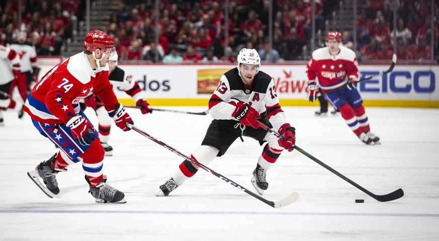 New Jersey Devils center Nico Hischier (13), from Switzerland, moves the puck past Washington Capitals defenseman John Carlson (74) during the third period of an NHL hockey game Saturday, Jan. 11, 202 ...