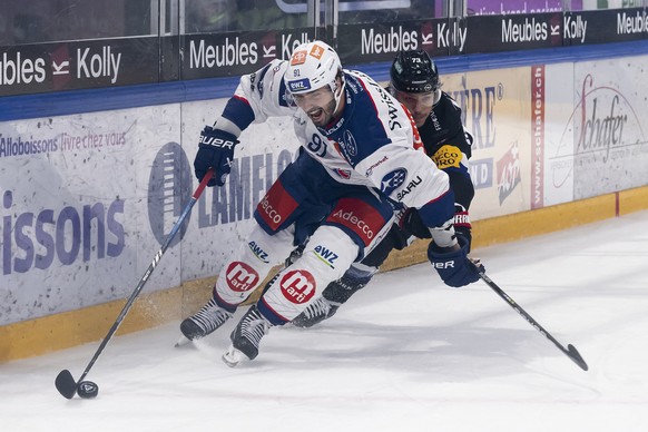 Zuerichs Denis Hollenstein, links, und der Freiburger Sandro Schmid, rechts, kaempfen um den Puck, beim Eishockey Meisterschaftsspiel der National League A zwischen dem HC Fribourg Gotteron und ZSC Li ...