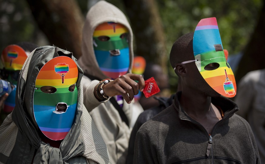 FILE---- In this file photo of Monday Feb. 10, 2014, Kenyan people who identify as gay and lesbian and others supporting their cause, wear masks to preserve their anonymity and one holds out a wrapped ...