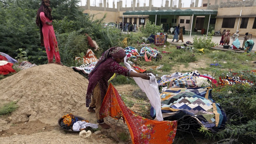 Pakistani women wash clothes on the grounds of a government college building after fleeing their flood-hit homes, in Karachi, Pakistan, Monday, Aug. 29, 2022. International aid was reaching Pakistan o ...