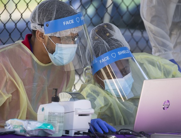 epa08748971 Staff members of the Whittier Street Health Center wear face shields while checking in patients at a pop up coronavirus testing center in Boston, Massachusetts, USA, 15 October 2020. The r ...