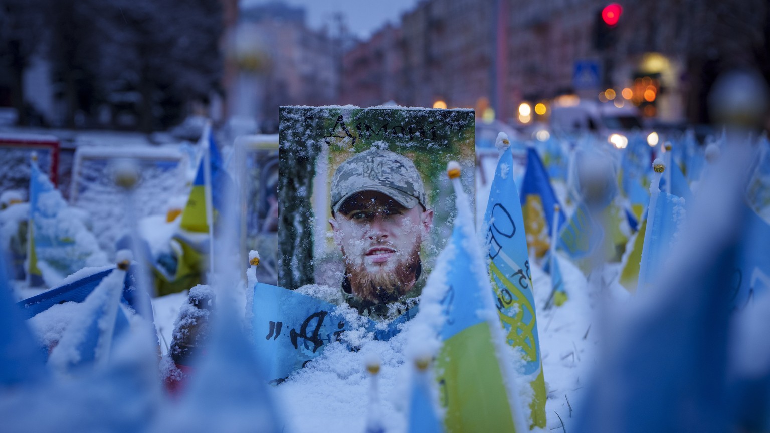 Snowflakes cover the photograph of a fallen Ukrainian serviceman downtown Kyiv, Ukraine, Tuesday, March 12, 2024. (AP Photo/Vadim Ghirda)