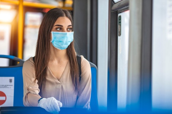 Eine Frau mit Maske und Handschuhen im Bus.